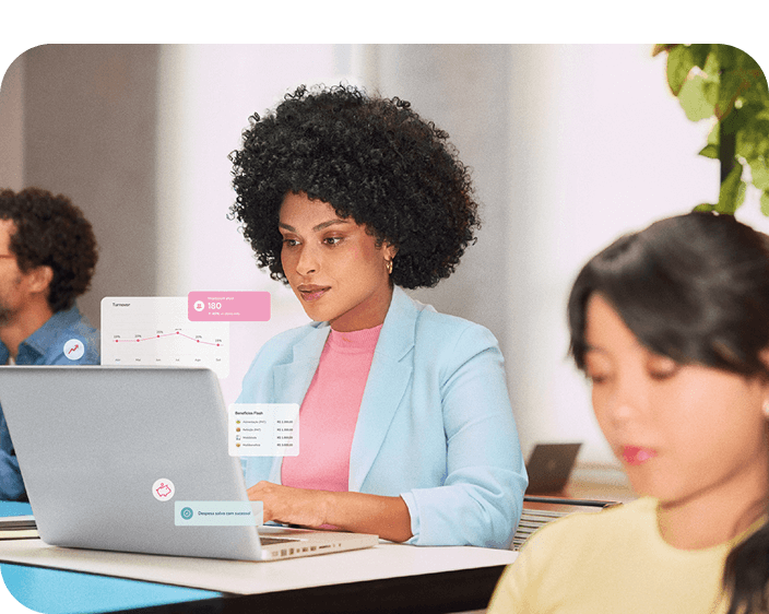 Em um ambiente de trabalho colaborativo, uma profissional mantém o foco em seu trabalho no laptop.