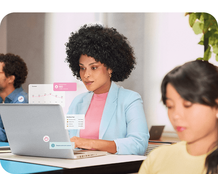 Em um ambiente de trabalho colaborativo, uma profissional mantém o foco em seu trabalho no laptop.